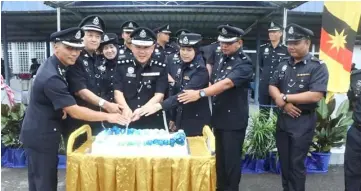  ??  ?? Ng (centre) and his deputy Supt Abang Junaidi Abang Anuar (second left) join others to cut a cake to celebrate birthdays of those that fall in July.