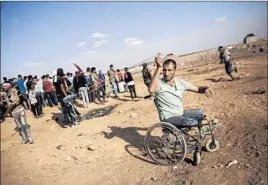  ??  ?? SABIR ASHQAR, who lost his legs in the 2008-2009 Gaza war, uses a slingshot during a protest near the border fence in a camp east of Gaza City on Friday.