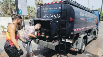  ??  ?? Workers fill diesel into their small tanker truck to sell it for the private power generators in Beirut after the country plunged into darkness amid fuel shortages.