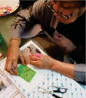  ??  ?? Hajah Rosmaniar painstakin­gly doing her diamond painting.