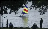  ?? DON CAMPBELL/THE HERALD-PALLADIUM VIA AP ?? A sailor with the St. Joseph Junior Foundation Summer Sailling School cruises past fishermen along the St. Joseph River in St. Joseph, Mich., June 15.