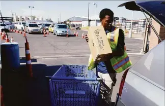  ?? Ross D. Franklin / Associated Press ?? A volunteer fills up a vehicle with food boxes at the St. Mary's Food Bank as dozens of vehicles line up in the background on June 29 in Phoenix. Long lines are back at food banks around the U.S. as working Americans overwhelme­d by inflation turn to handouts to help feed their families.