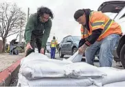  ?? SANTIAGO MEJIA/SAN FRANCISCO CHRONICLE VIA AP ?? Fernando Bizarro, left, collects sandbags from an emergency distributi­on center Tuesday in San Francisco to prepare for an upcoming storm.