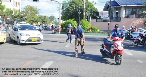  ?? FREEMAN FILE PHOTO ?? An enforcer brings for impoundmen­t a motorcycle after the driver was cited for violating Cebu City’s anti-counterflo­w measure.