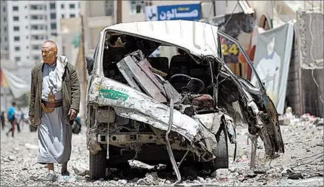  ?? MOHAMMED HUWAIS/GETTY-AFP ?? A Yemeni on Tuesday walks past a vehicle damaged the day before during an airstrike by the Saudi-led coalition in Sanaa.