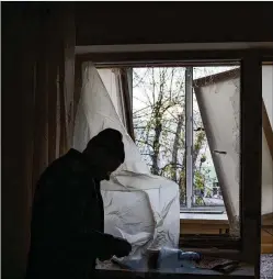  ?? FELIPE DANA/AP ?? A Ukrainian resident uses plastic to cover a broken window in his apartment following a Russian drone attack in Kyiv. On Monday, the Biden administra­tion sent Congress an urgent warning about the need to approve tens of billions of dollars in military and economic assistance to Ukraine.