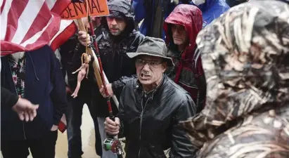  ??  ?? A man with a flag that has a doll with a noose around its neck grimaces as he comes to the front of the stage during a protest against the state's stay-at-home order at the Michigan Capitol in Lansing, Mich., Thursday