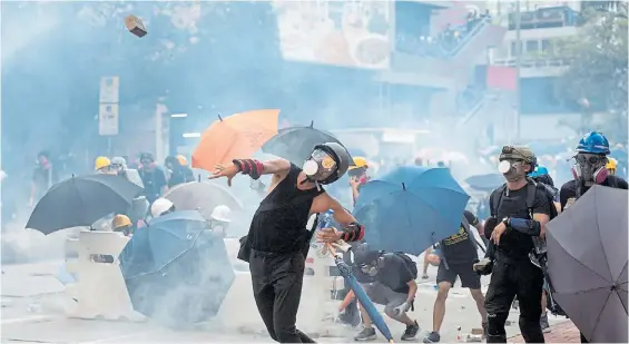  ?? EFE ?? Choques. Manifestan­tes lanzan ladrillos contra la policía que reprimió ayer con gases lacrimógen­os otra protesta en los barrios de Hong Kong.
