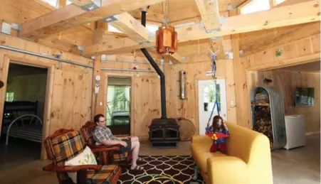  ?? TRACY HANES PHOTOS ?? Jason Rioux watches his daughter Renee play in their cottage’s octagonal living room, from which other rooms fan out like spokes. A single solar panel on the side of the Octopod cottage powers the water pump, which takes water to a gravity-fed storage...