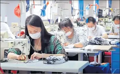  ??  ?? Workers manufactur­ing face masks at a factory in China