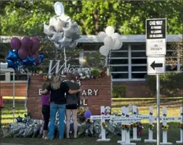  ?? Jae C. Hong/Associated Press ?? A family pays their respects Thursday next to crosses bearing the names of Tuesday’s shooting victims at Robb Elementary School in Uvalde, Texas.