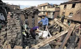  ?? AP PHOTOS ?? A Nepalese family collects belongings Monday from their home in Bhaktapur on the outskirts of Kathmandu, Nepal, where many buildings were reduced to rubble.