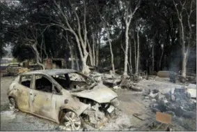  ?? MARCIO JOSE SANCHEZ — THE ASSOCIATED PRESS ?? A burned car is seen in front of a wildfire ravaged home Tuesday in Lakeport Battalion Chief John Messina said Tuesday fire crews slowed the spread of one of the blazes into towns near Clear Lake, including Lakeport, a city of 5,000. He says the fire instead spread into the Mendocino National Forest.