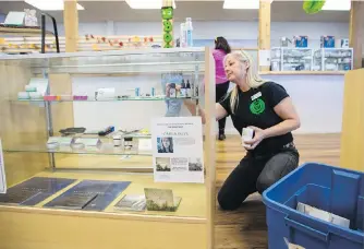  ??  ?? Above: Floor supervisor Debbie Crookes packs up inventory before closing at Green Hart Health and Wellness Inc. in Victoria on Tuesday. Top: A man smokes a joint during the annual 4/20 marijuana celebratio­n on Parliament Hill in Ottawa on April 20.