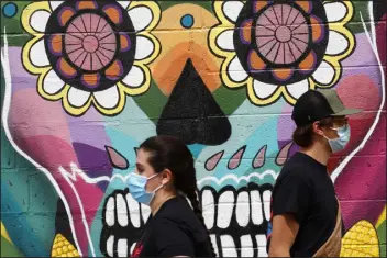  ?? KEVIN MOHATT — SPECIAL TO THE DENVER POST ?? People walk past a mural outside Cultura Chocolate in Denver’s Westwood neighborho­od.