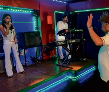  ?? REHEARSAL Joanna Talibong, a single mother singing for her life, practices on a mock-up stage in a music studio as she and Jason Panggoy (center) are coached by a music director.
AFP ??