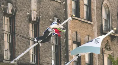  ?? ADAM GRAY / GETTY IMAGES ?? A man wearing an Israeli flag climbs a pole to remove a Palestinia­n flag from a Columbia University fraternity building Friday in New York City. America's top universiti­es have become battlegrou­nds over the war in Gaza.