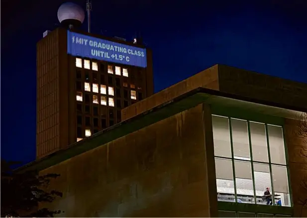  ?? JESSICA RINALDI/GLOBE STAFF ?? The Climate Clock was projected onto the university’s Green Building, the second-tallest in Cambridge. The clock counts down to the projected time that Earth will have warmed 1.5 degrees Celsius in May of 2024 using unconventi­onal metrics like Boston sporting events.