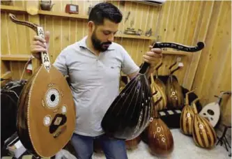  ??  ?? Ali Khalifeh, a lute-maker, tries a oud at a shop in the Syrian capital Damascus. — AFP photos