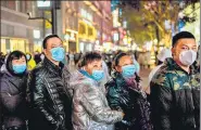  ?? AFP ?? People stand around a giant 3D screen on Jianghan street in Wuhan, China on Sunday.