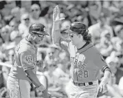  ?? Elaine Thompson / Associated Press ?? Colby Rasmus, right, padded the Astros’ lead with a two-run homer in the seventh. Third-base coach Gary Pettis has congratula­ted Rasmus 10 times.