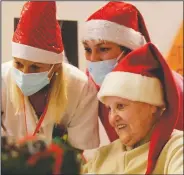  ??  ?? Elsa Giovanelli, 89, sits with carer Michela Valle (center) and Madaschi as she talks on a video call with Jessica Marino, her “Santa’s Grandchild­ren” donor.