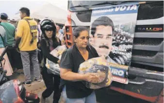  ?? AP ?? Reparto. Varias personas cargan fundas con alimentos proporcion­ados por el gobierno de Nicolás Maduro, cerca del puente internacio­nal Tienditas, en las afueras de Ureña, ayer en Venezuela.