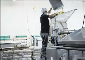  ??  ?? Erik Ramos drops a mix of corn flour to make tortillas at T.I. Foods.