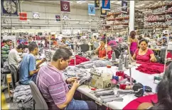  ?? MERIDITH KOHUT/THE NEW YORK TIMES ?? Workers fill T-shirt orders from U.S. universiti­es at League factory in Ciudad Arce, El Salvador.