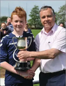  ?? Picture: Ken Finegan ?? Nathan Commins, the Ardee Celtic captain, receives the U-13 Premier Division trophy from Michael Dillon, chairman of the Dundalk Schoolboys League.