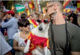  ??  ?? A man carries a dog wearing the Spanish colors while people celebrate “Dia de la Hispanidad” or Spain's National Day in Barcelona on Thursday. —