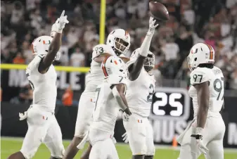  ?? Lynne Sladky / Associated Press ?? Miami defensive back Trajan Bandy (with ball) celebrates after recovering a fumble during the second half of the Hurricanes’ 179 victory over No. 20 Virginia in Miami Gardens, Fla.