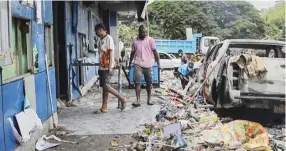  ?? DARRELL TOLL/AFPTV/AGENCE FRANCE-PRESSE ?? VIDEO footage taken shows people walking past debris in front of buildings damaged during riots in Port Moresby. Papua New Guinea’s prime minister declared a 14-day state of emergency in the capital, after 15 people were killed in riots as crowds looted and burned shops.