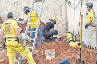  ??  ?? Bomberos voluntario­s tratan de localizar el cuerpo del obrero que quedó atrapado en el pozo que cavaba con otro trabajador, cuando se desmoronó el montículo de tierra.