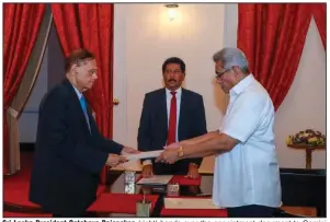  ?? (AP/Sri Lankan President’s Office) ?? Sri Lanka President Gotabaya Rajapaksa (right) hands over the appointmen­t document to Gamini Lakshman Peiris after he took his oath of office as the new foreign minister Saturday in Colombo, Sri Lanka.