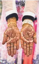  ??  ?? Heda holds out her hands covered with intricate designs in henna on the sangeet night, a pre-wedding celebratio­n. The designs are heavy with symbolism for the couple.