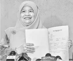  ??  ?? Noraihan holding up the police report lodged against a former MACC senior officer at a press conference. — Bernama photo