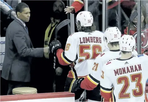  ?? JULIO CORTEZ/ THE ASSOCIATED PRESS ?? Calgary Flames’ assistant coach Paul Jerrard, left, fist- bumps left winger Ryan Lomberg after a win against the New Jersey Devils on Feb. 8. The NHL has almost two dozen black players but just one black official in linesman Shandor Alphonso and one...