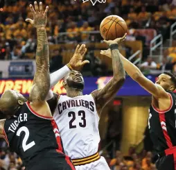  ?? (Reuters) ?? CLEVELAND CAVALIERS forward LeBron James (center) goes up to the hoop between Toronto Raptors defenders P.J. Tucker and Norman Powell for two of his game-high 35 points in the Cavs’ 116-105 home victory on Monday night in Game 1 of the clubs’ Eastern...