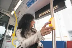  ??  ?? Gina Gonzales presses a stop button on a new Muni light-rail car, one of the five new cars put in service since November. The agency hopes to start putting a new car on the tracks every week by the end of March. Top: Lucas Smith and Doug Lee talk by...