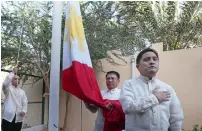  ??  ?? Paul Raymund Cortes (right) sings the Philippine national anthem during the flag-raising ceremony. — Photo by Dhes Handumon