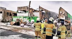  ?? FOTO: STEPHAN KÖHLEN ?? Feuerwehrl­eute stehen vor der abgebrannt­en Lagerhalle an der Heinrich-Hertz-Straße.