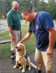  ?? DONNA ROVINS — DIGITAL FIRST MEDIA ?? Birdsboro-Union Fire Department Fire Chief Scott Kulp, right, meets seizure response dog Dexter. Birdsboro Borough Manager Aaron Durso, left, suffers from frequent seizures, and recently took Dexter to meet Birdsboro’s first responders. Dexter joined...