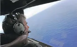  ??  ?? In this file photo taken from a Royal New Zealand Airforce (RNZAF) P-3K2-Orion aircraft on April 13, 2014 shows co-pilot and Squadron Leader Brett McKenzie helping to look for objects during the search for missing Malaysia Airlines flight MH370, off...