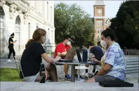  ?? JOSHUA A. BICKEL — THE COLUMBUS DISPATCH VIA AP ?? Students Jessica DeSena, right, and Camden Coggburn, left, both from Columbus, sit outside Thompson Library, Aug. 25, during the first day of fall classes at Ohio State University in Columbus, Ohio. Colleges in the U.S. have seen a sharp enrollment drop among internatio­nal students this fall. University administra­tors say a number of hurdles and new policies brought on by the coronaviru­s pandemic are to blame.