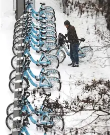  ??  ?? left A Divvy bicycle rider deposits his bike in a rental kiosk Friday in Chicago as a winter storm makes its way through several Midwest states. The upper Midwest is preparing for a wintry blast as a winter storm is expected across the region, with...