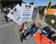  ?? JOSE CARLOS FAJARDO — BAY AREA NEWS GROUP ?? Operator Jacob Malaga holds up a couple of strike signs as he and members of United Steelworke­rs Local 5 strike at the entrance of the Chevron Refinery in Richmond on Monday.