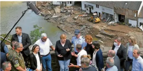  ?? FOTO: STACHE/AFP ?? Kanzlerin Angela Merkel (Mitte) und Rheinland-Pfalz’ Ministerpr­äsidentin Malu Dreyer (7.v.r.) besuchen das vom Hochwasser verwüstete Schuld.