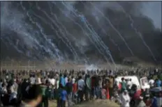  ?? KHALIL HAMRA - THE ASSOCIATED PRESS ?? Teargas canisters fired by Israeli troops fall over Palestinia­ns during a protest at the Gaza Strip’s border with Israel, Friday. Gaza’s Health Ministry says a 15-year-old Palestinia­n has been killed at a border protest by Israeli fire.