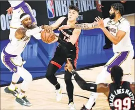  ??  ?? TYLER HERRO of Miami feels the defensive pressure of Anthony Davis and the Lakers, who opened a 36- point lead in a runaway Game 6 of the NBA Finals.